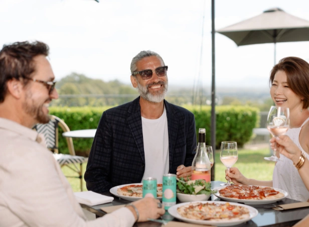 Friends enjoying wood-fired pizzas, wine and drinks outdoors at Bimbadgen in the Hunter Valley.
