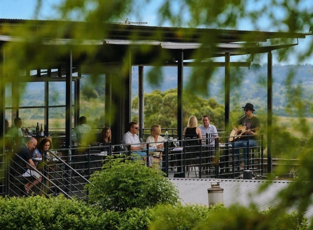Guests dining on the Esca balcony while an acoustic guitarist performs, with Hunter Valley vineyards in the background.