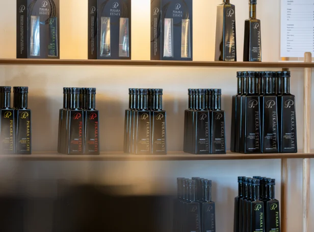 Pukara Estate olive oil and vinegar bottles arranged on timber display shelves alongside boxed gift sets.